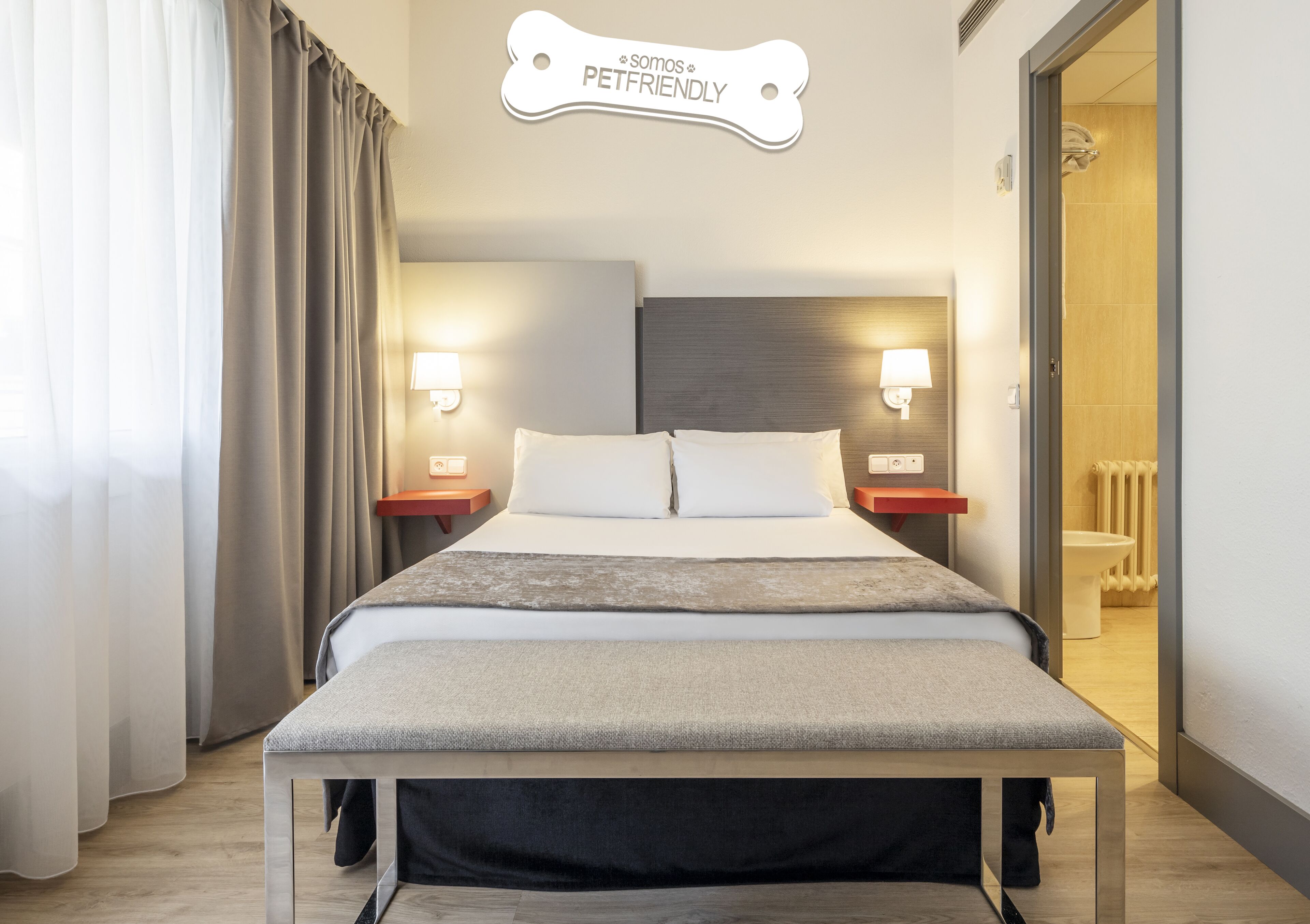 Ein Hotelzimmer mit Bett, Nachttischen, einem an der Wand befestigten Schild für Haustiere und Blick ins Badezimmer.