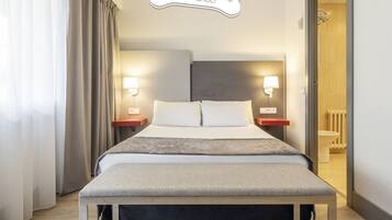 Ein Hotelzimmer mit Bett, Nachttischen, einem an der Wand befestigten Schild für Haustiere und Blick ins Badezimmer.
