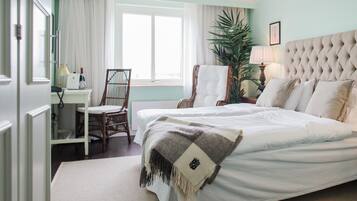 Una habitación de hotel con una cama grande, una silla, un escritorio con lámpara y una ventana con cortinas.