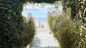 A stone pathway leading to a beach, surrounded by lush greenery.