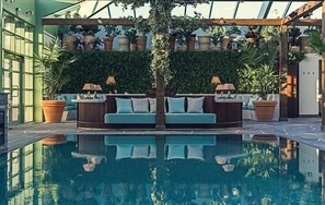 A pool area with a sofa and lamps, surrounded by potted plants and a green wall. - Falkenberg Strandbad (Falkenberg)