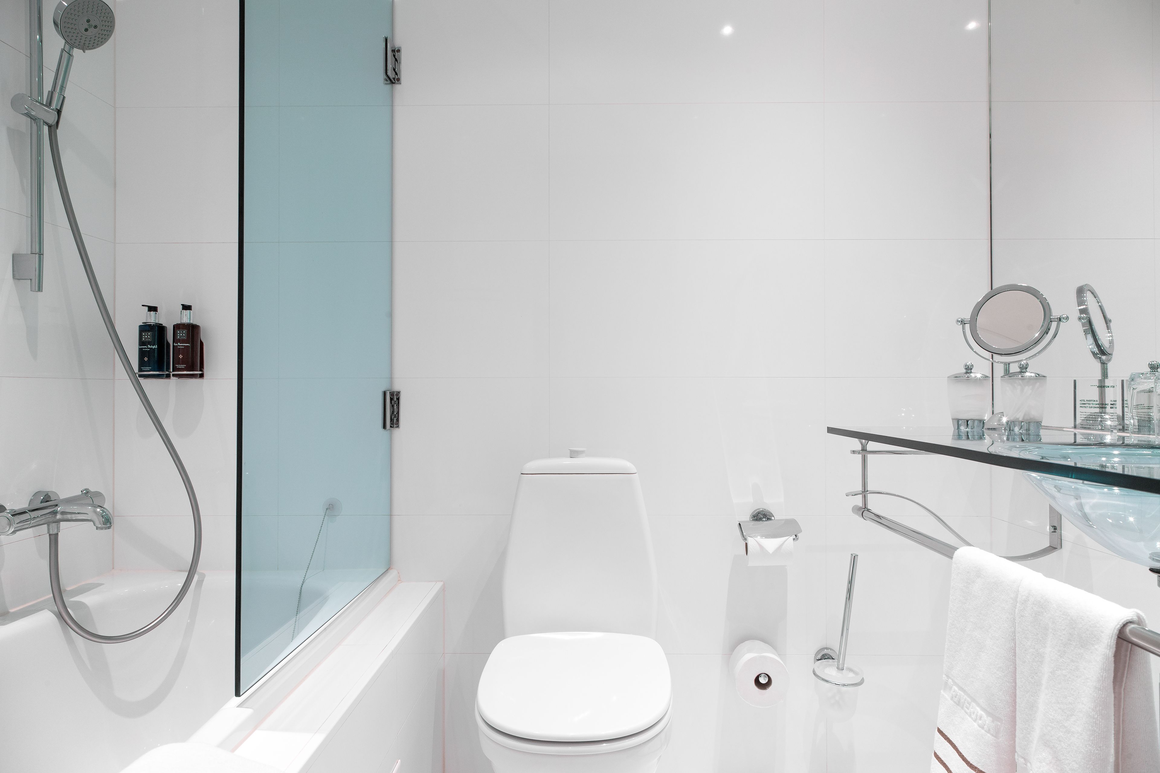 Une salle de bain moderne avec une douche à parois de verre, des toilettes blanches, un lavabo en verre et un porte-serviettes.