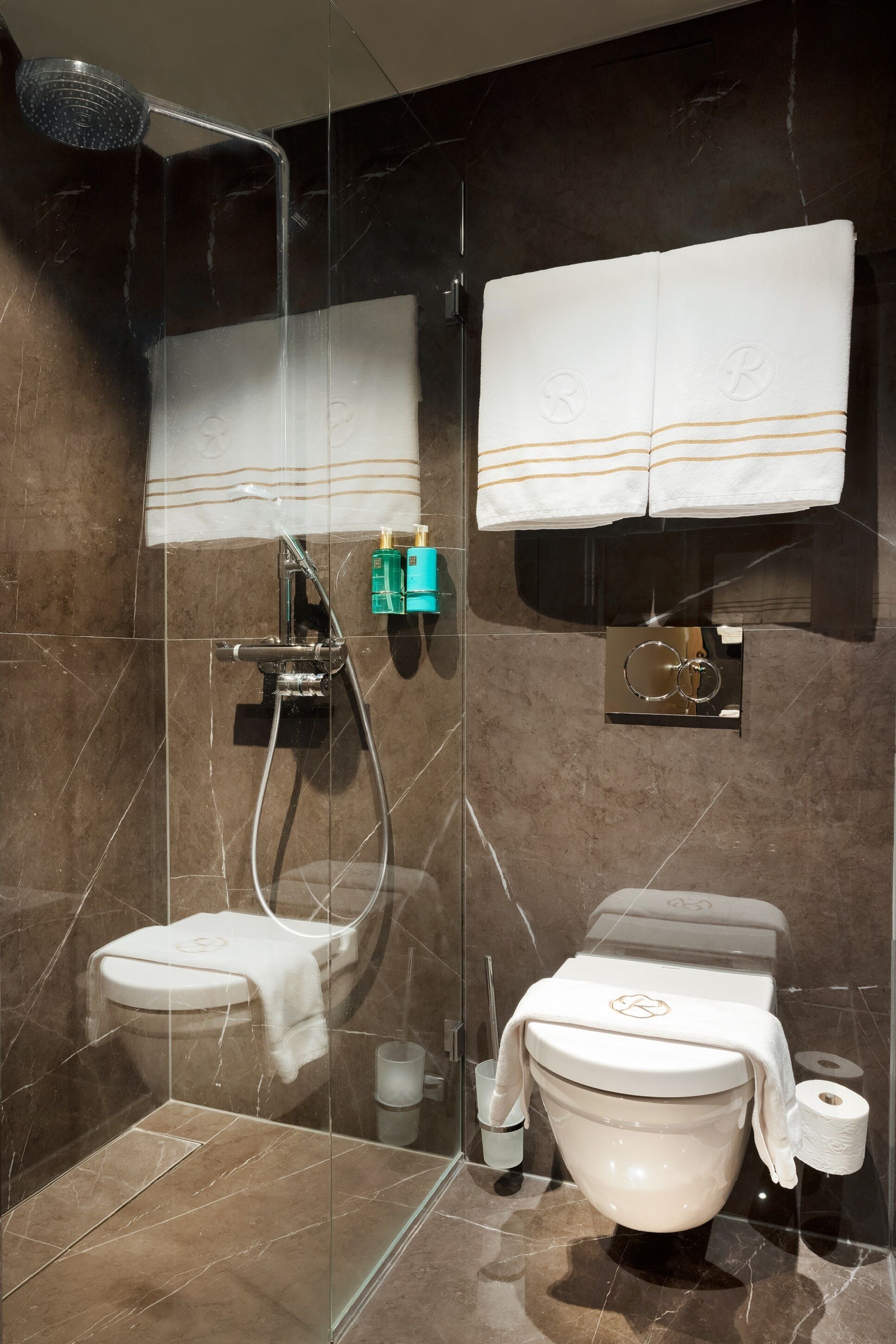A modern bathroom with a glass-enclosed shower, a toilet, and a bidet.