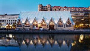 A building with a unique architectural design featuring a series of pointed arches and a reflective roof. - Hotel Riverton (Gothenburg)