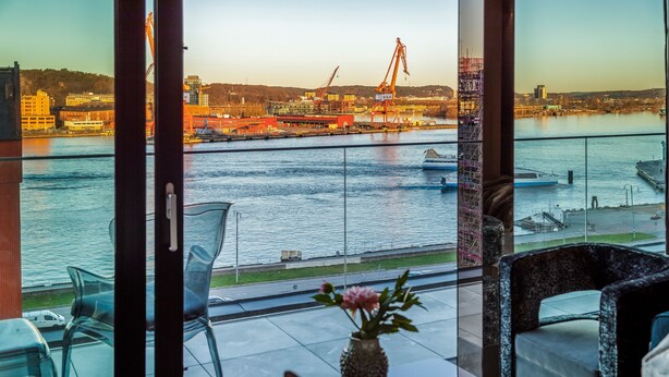 A balcony with a view of a harbor, including cranes and boats. - Hotel Riverton (Gothenburg)