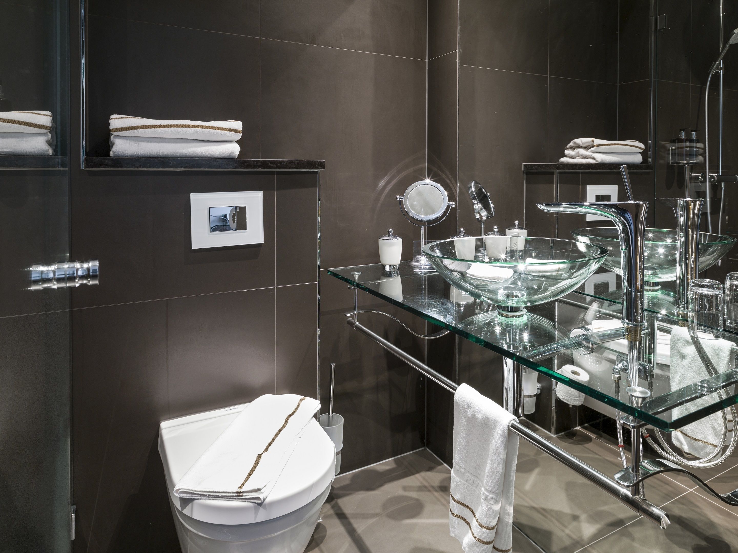 Une salle de bain moderne avec un lavabo en verre, des toilettes et un miroir.