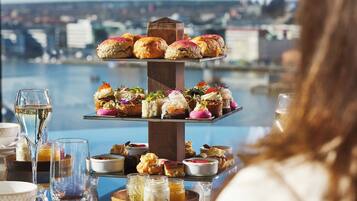 A tiered dessert display with various pastries and a cityscape view in the background.