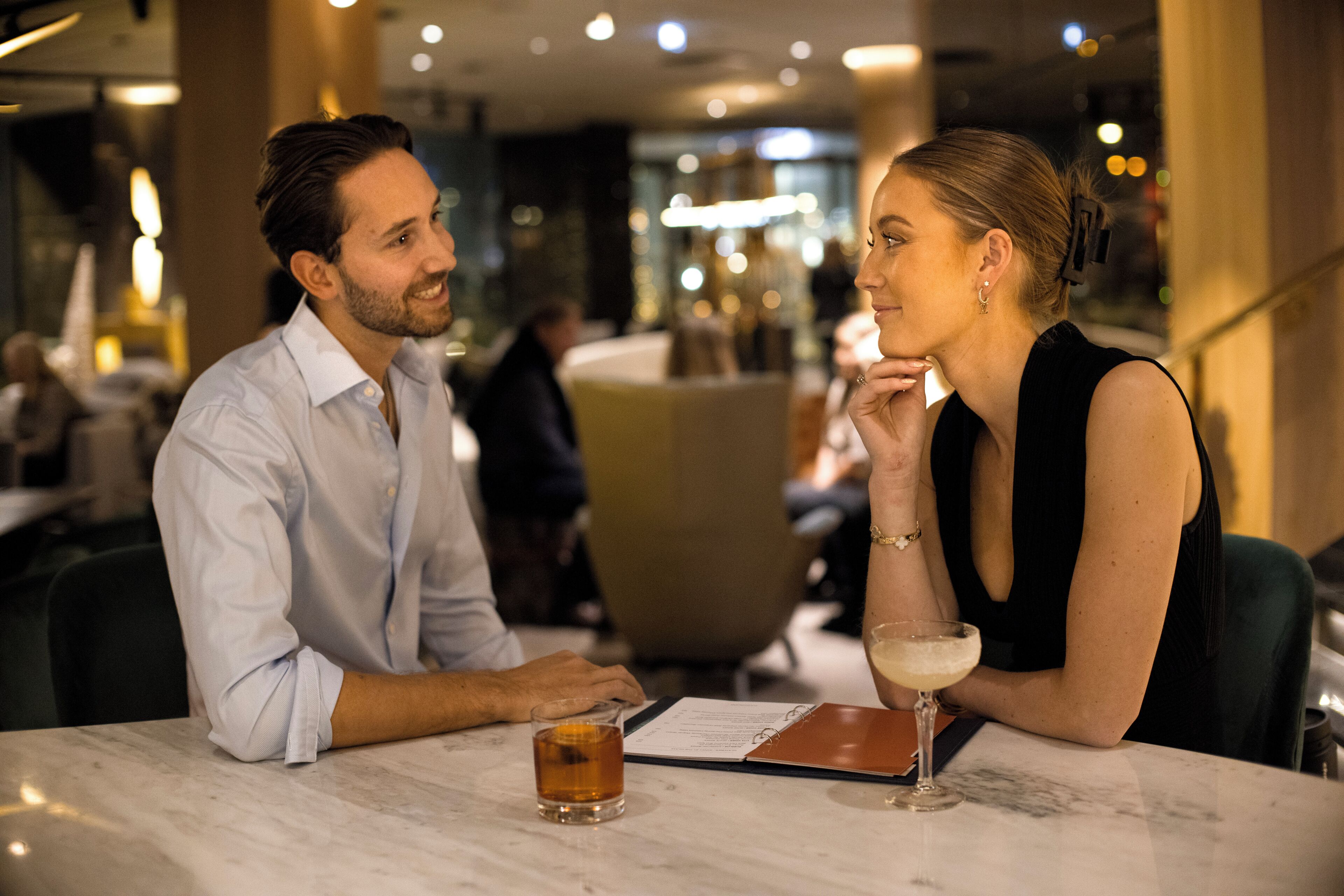 Ein Paar isst in einem Restaurant, auf dem Tisch liegen eine Speisekarte und Getränke.