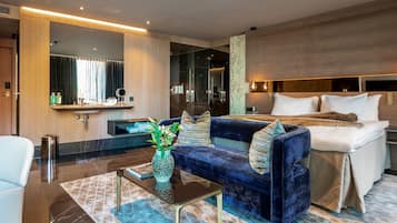 Une chambre d’hôtel moderne avec un grand lit, un canapé, une petite table avec un vase et un miroir.
