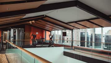 A modern interior with a glass railing, a staircase, and large windows offering a city view.