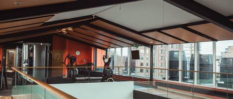 A modern interior with a glass railing, a staircase, and large windows offering a city view.