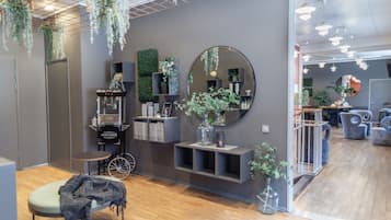 Un interior moderno con piso de madera, paredes grises, y una variedad de plantas y estantes.
