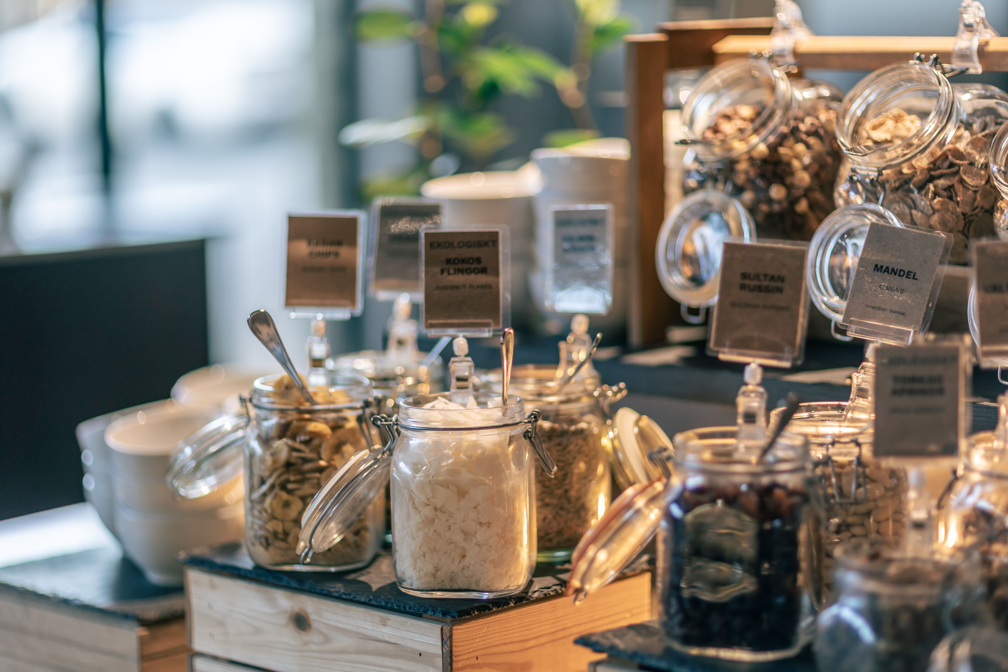 A display of various food items in glass jars with labels, arranged on a wooden surface.
