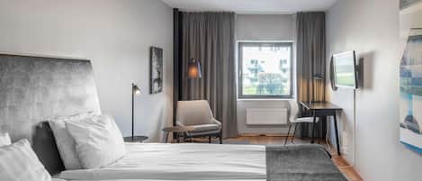 Una habitación de hotel moderna con una cama grande, un escritorio, una silla y un televisor.