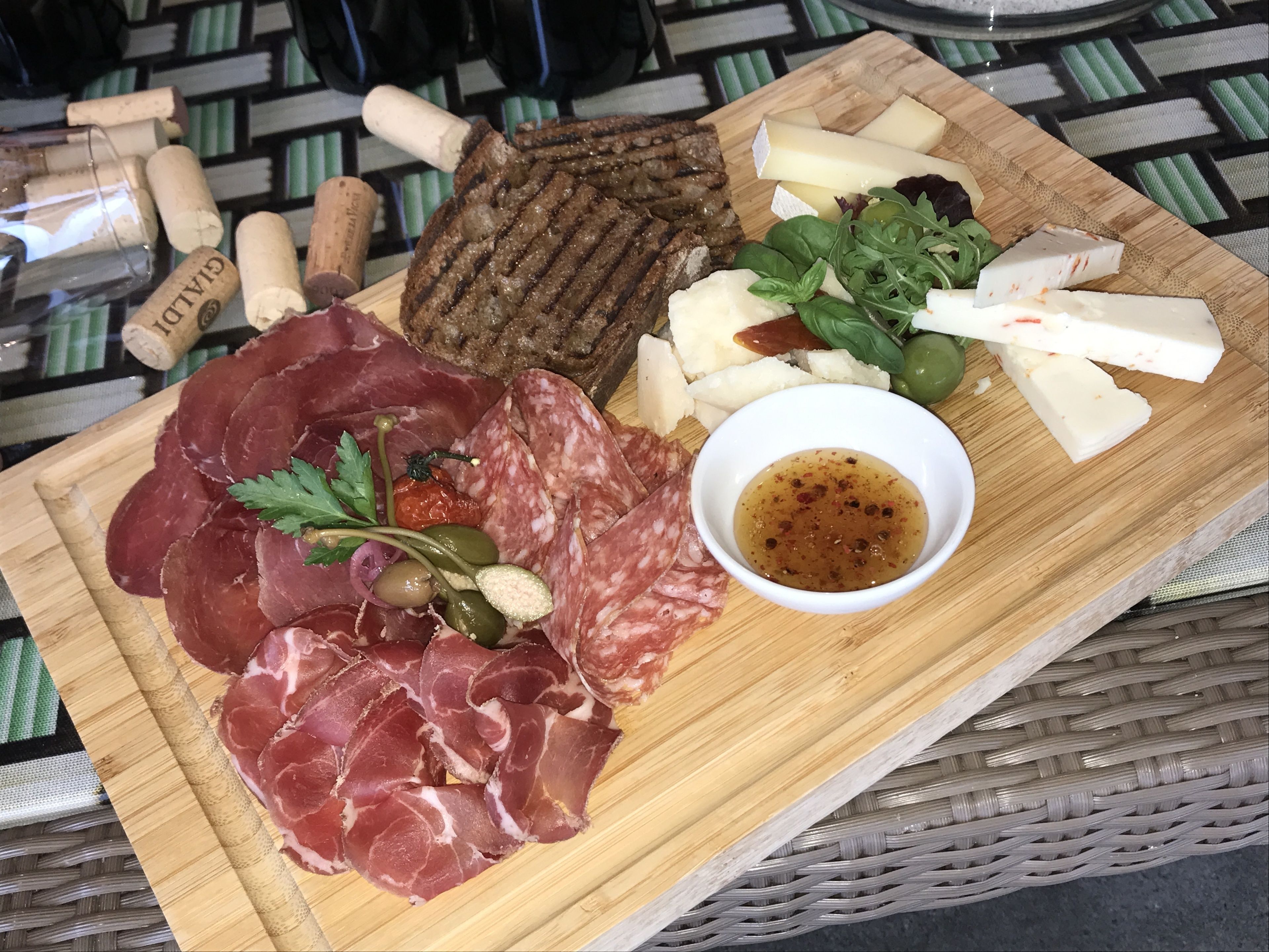 Un tagliere con salumi, formaggi e olive su un'asse di legno.