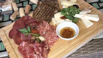 A charcuterie board with various meats, cheese, and olives on a wooden board.