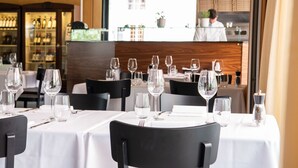 A restaurant with tables set for dining, a bar area with bottles, and a view of the street outside. - Tailormade Hotel AL GIARDINETTO Biasca (Biasca)