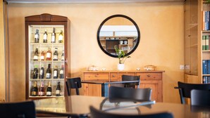 A dining area with a wooden table, black chairs, a wine refrigerator, a mirror, and a bookshelf. - Tailormade Hotel AL GIARDINETTO Biasca (Biasca)