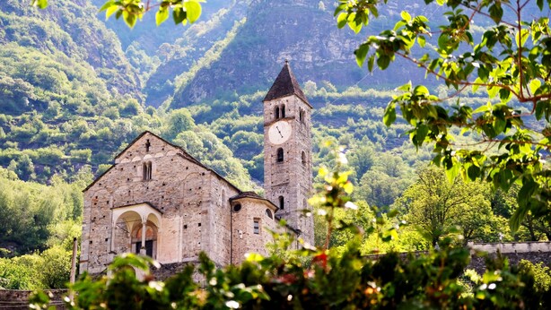 A historic stone building with a clock tower, surrounded by lush greenery and mountains. - Tailormade Hotel AL GIARDINETTO Biasca (Biasca)