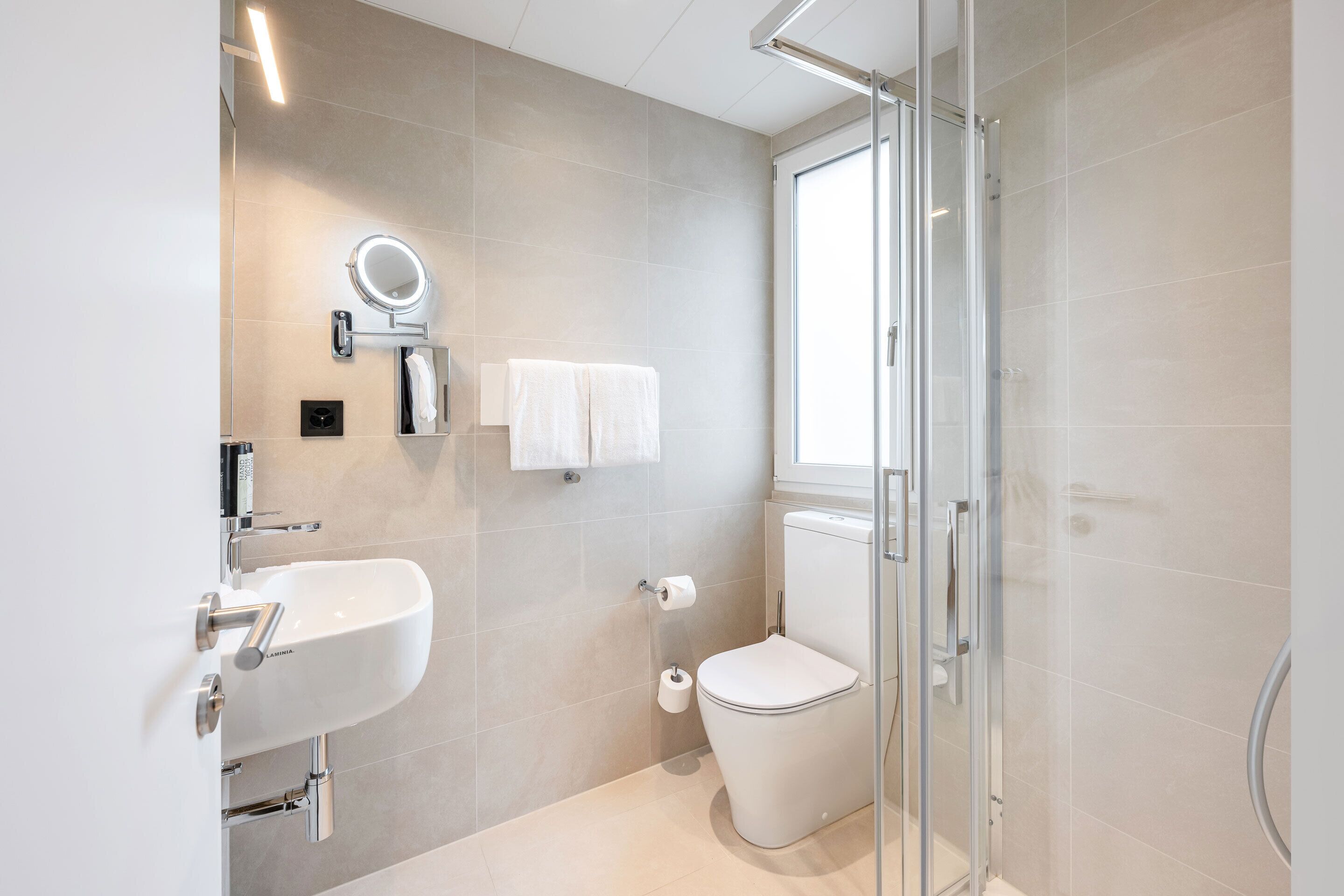 Ein modernes Badezimmer mit Duschkabine aus Glas, einem weißen Waschbecken und einer Toilette.
