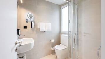 A modern bathroom with a glass shower enclosure, a white sink, and a toilet.