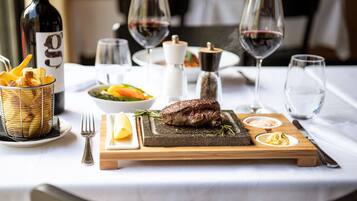 Een eettafel met een steak, salade en een broodmand.