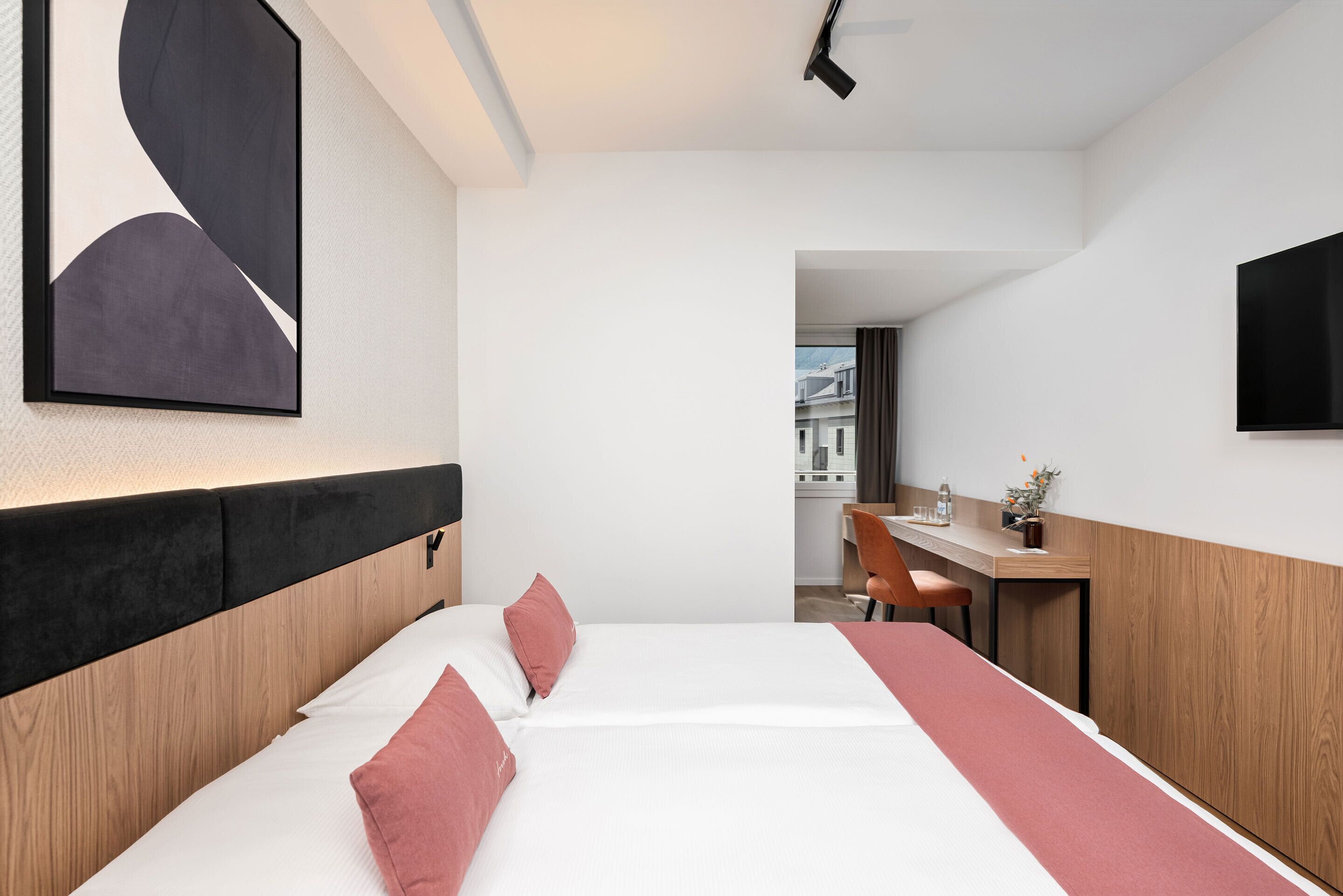 A hotel room with a bed, a desk, and a TV.
