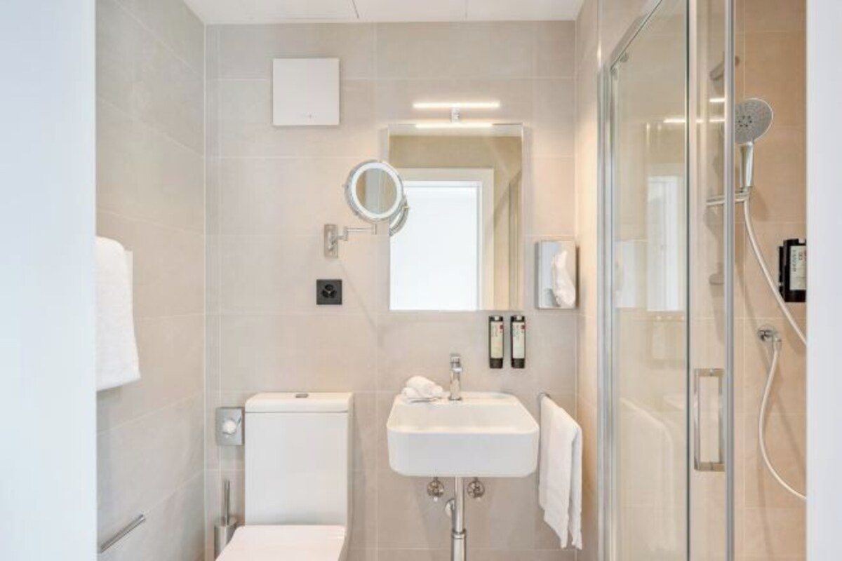 A modern bathroom with a toilet, sink, and glass shower enclosure.