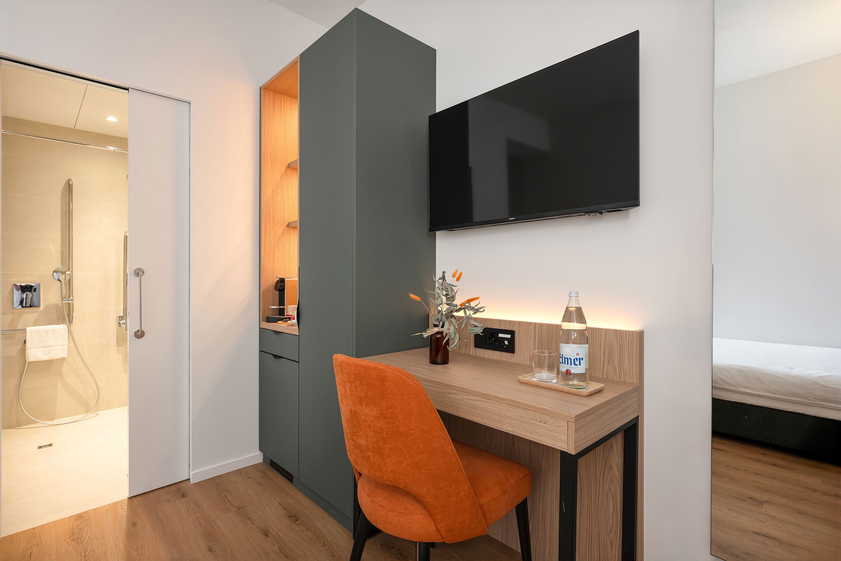 Una habitación de hotel moderna con escritorio, silla, televisor y cama.