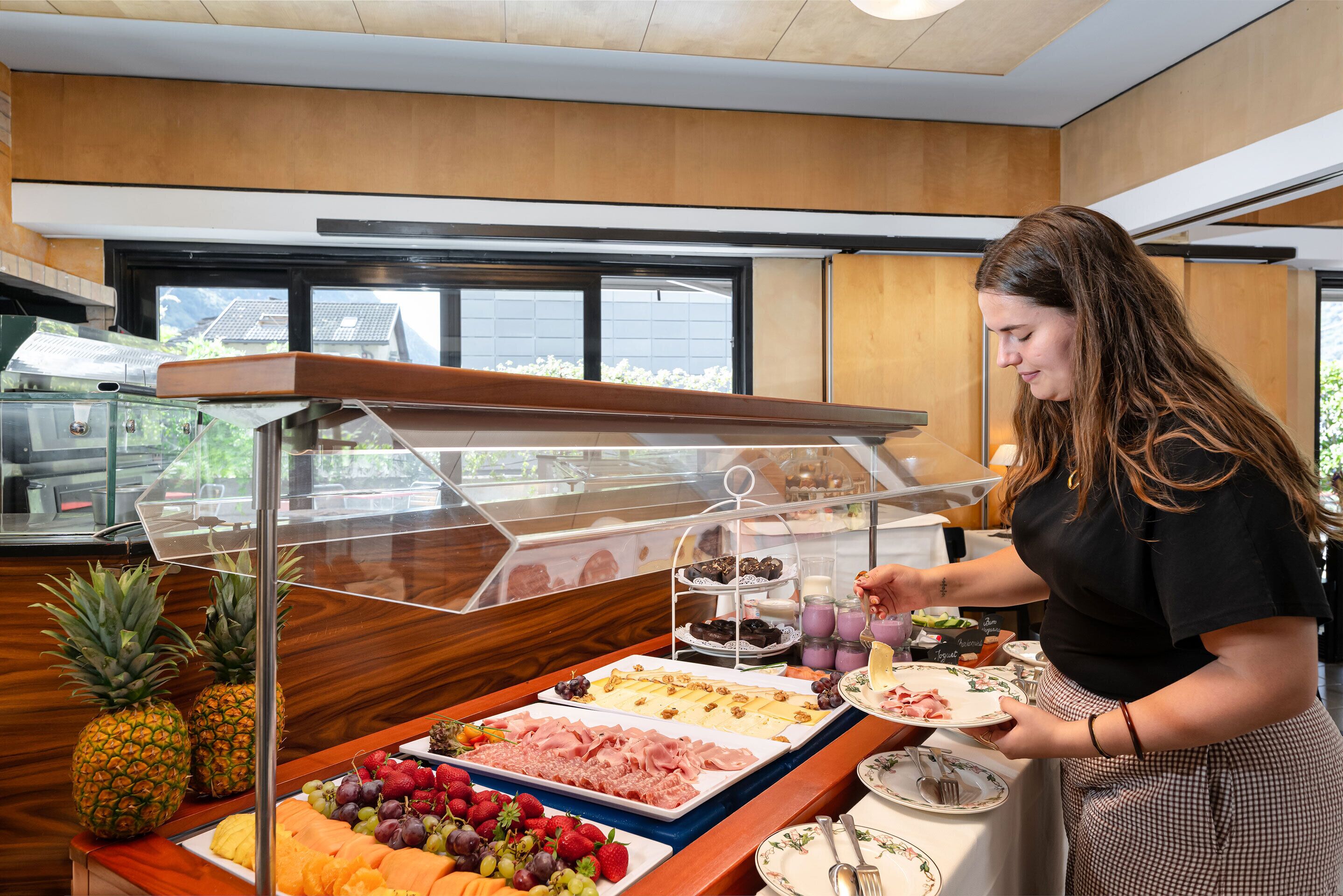 A buffet setup with various food items and a person serving.
