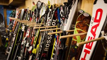A row of skis leaning against a wall in a storage area.