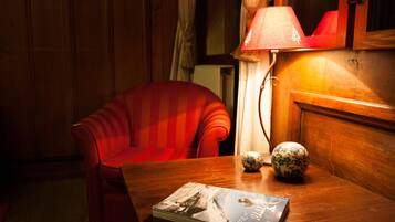 A wooden table with a magazine, two decorative vases, and a red chair in a warmly lit room.