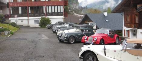 A row of vintage cars parked in front of a building with a balcony.