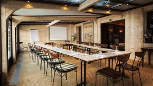 A conference room with a long table, chairs, a projector screen, and wooden walls. - Hotel Suisse (Champery)