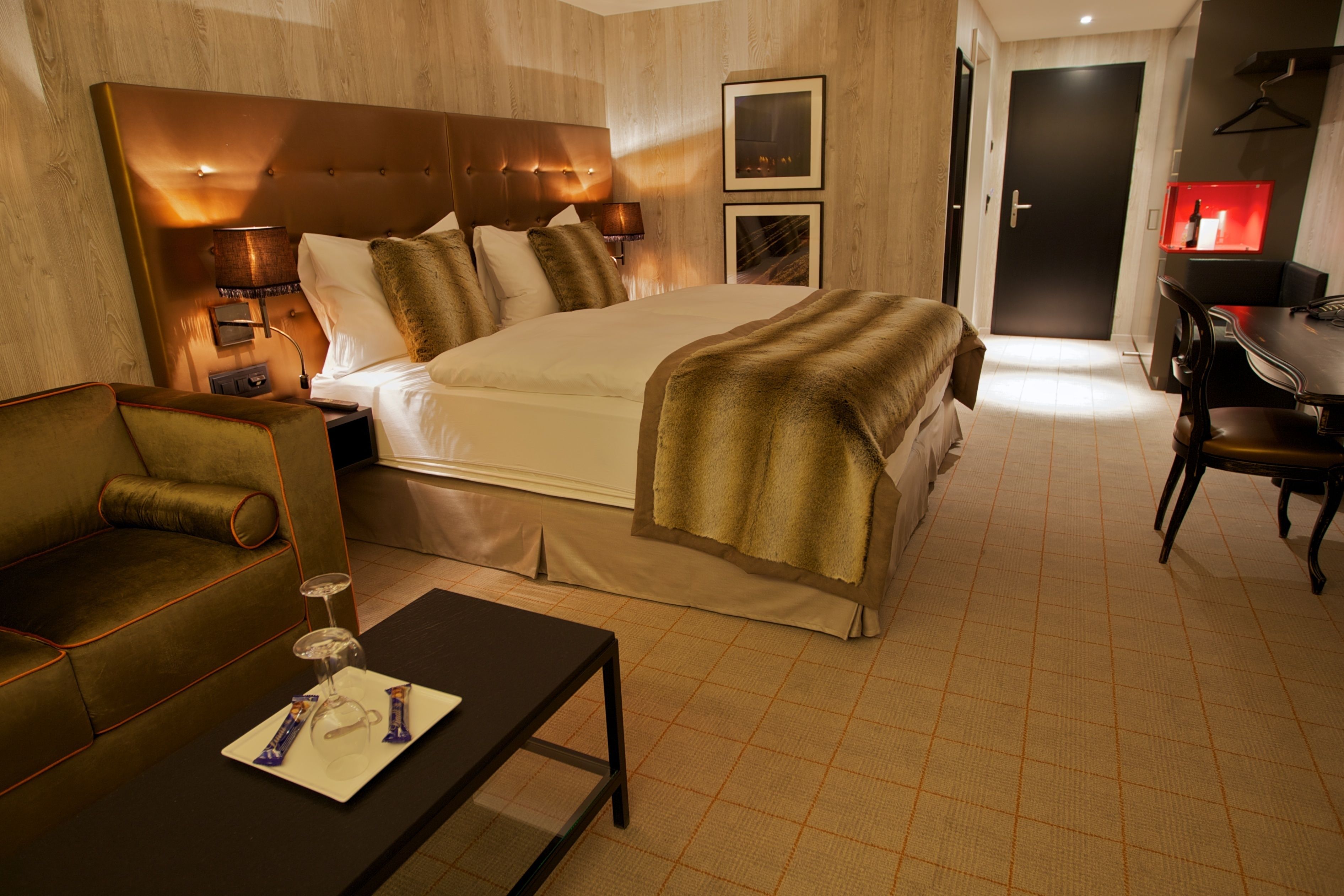 Een hotelkamer met een groot bed, een bank, een eettafel en een bureau.