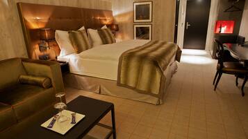 Een hotelkamer met een groot bed, een bank, een eettafel en een bureau.