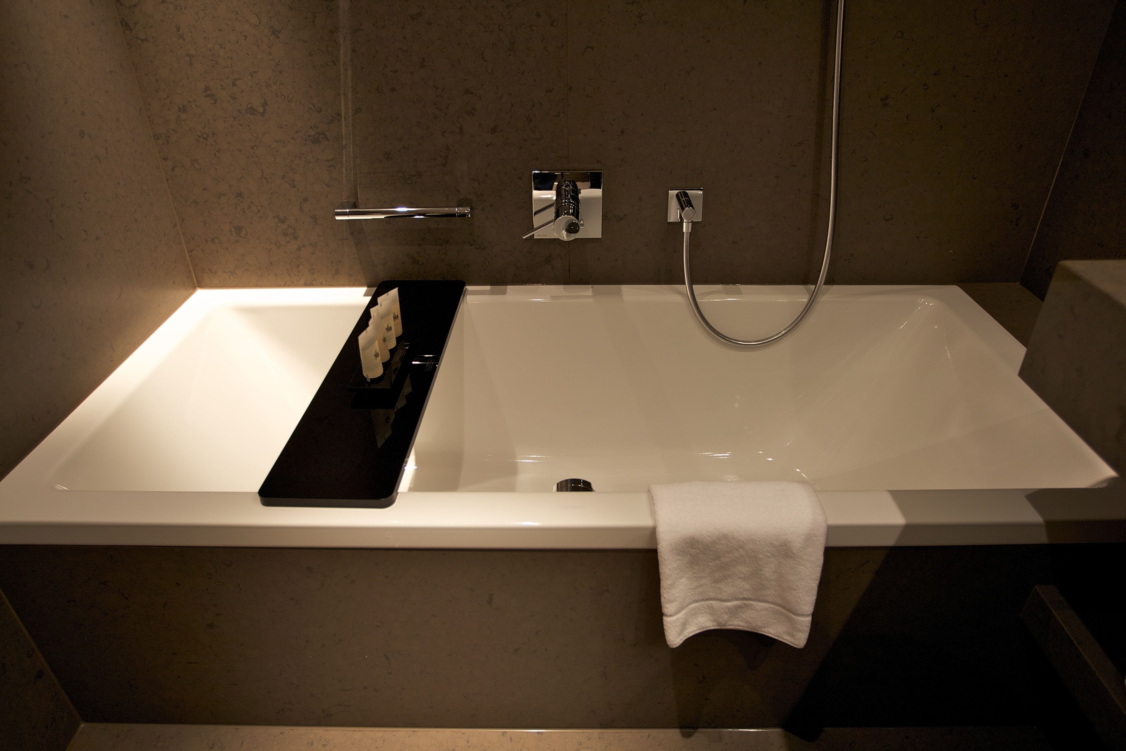 Ein modernes Badezimmer mit einer großen Badewanne, einer Handbrause und einem Handtuchhalter.