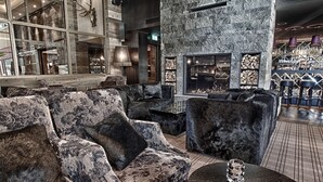 Un área de descanso moderna con sofás cómodos, chimenea y un bar con taburetes.