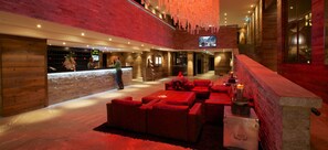 Relax in the hotel's inviting lobby, featuring a reception desk, comfortable seating area, and a staircase leading to the upper level.