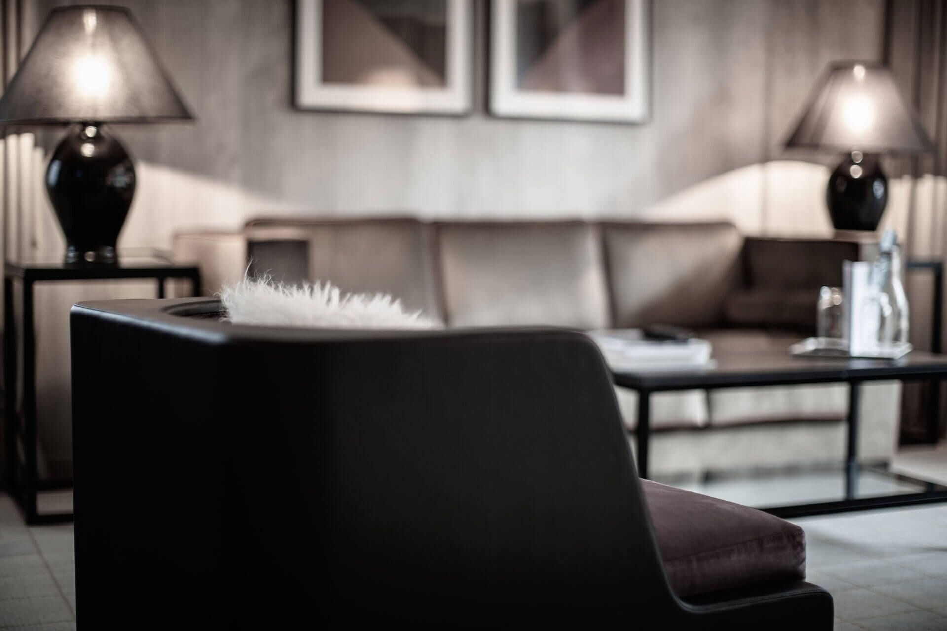 Una sala de estar moderna con un sofá oscuro, una mesa de centro y dos lámparas a cada lado.