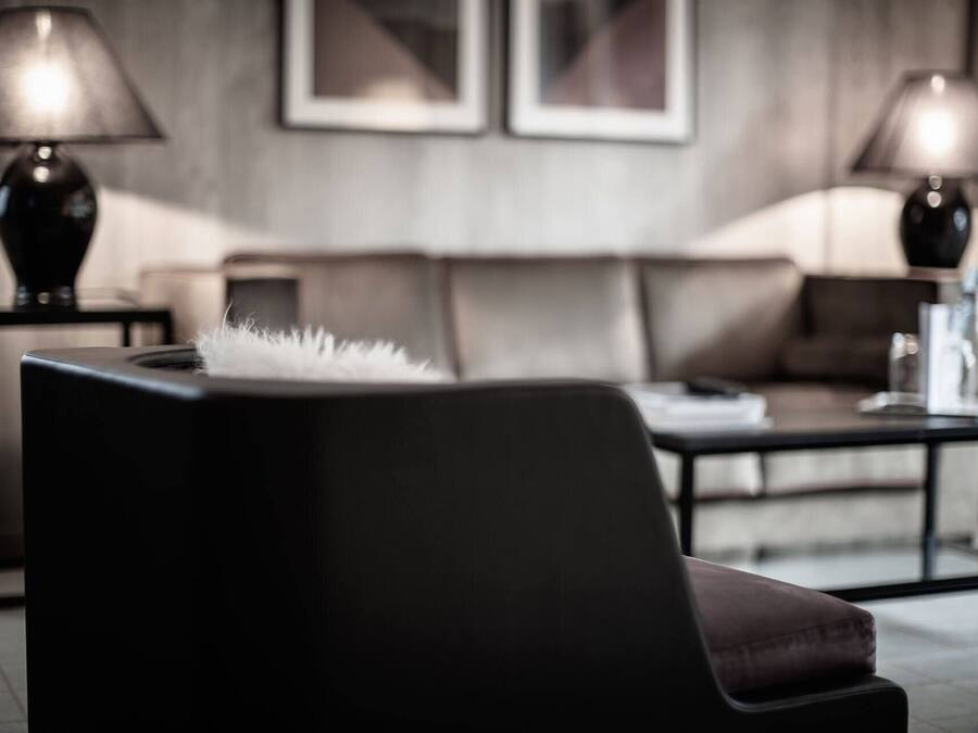 Una sala de estar moderna con un sofá oscuro, una mesa de centro y dos lámparas a cada lado.