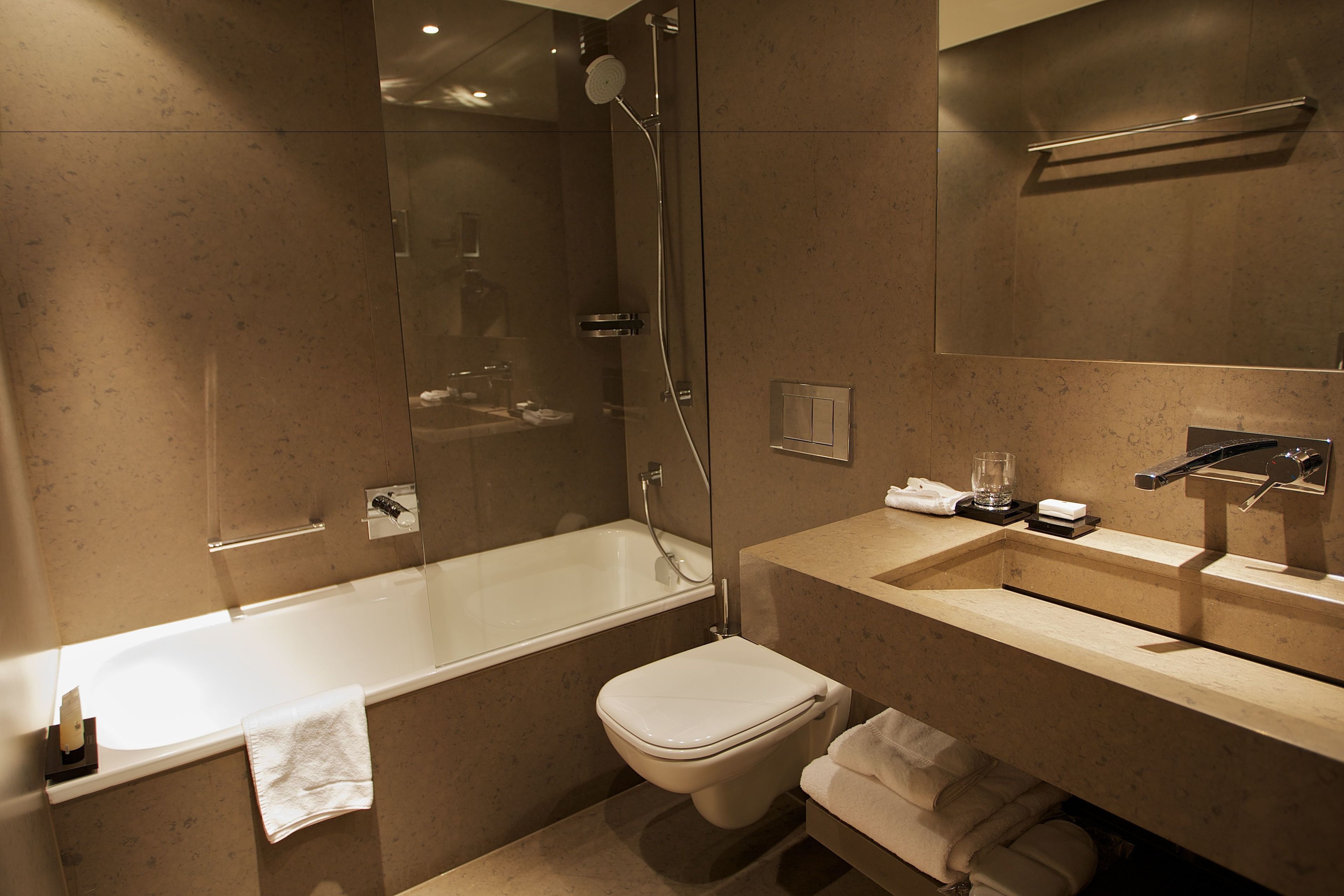 A modern bathroom with a glass-enclosed shower, a standalone toilet, and a vanity with a sink and mirror.