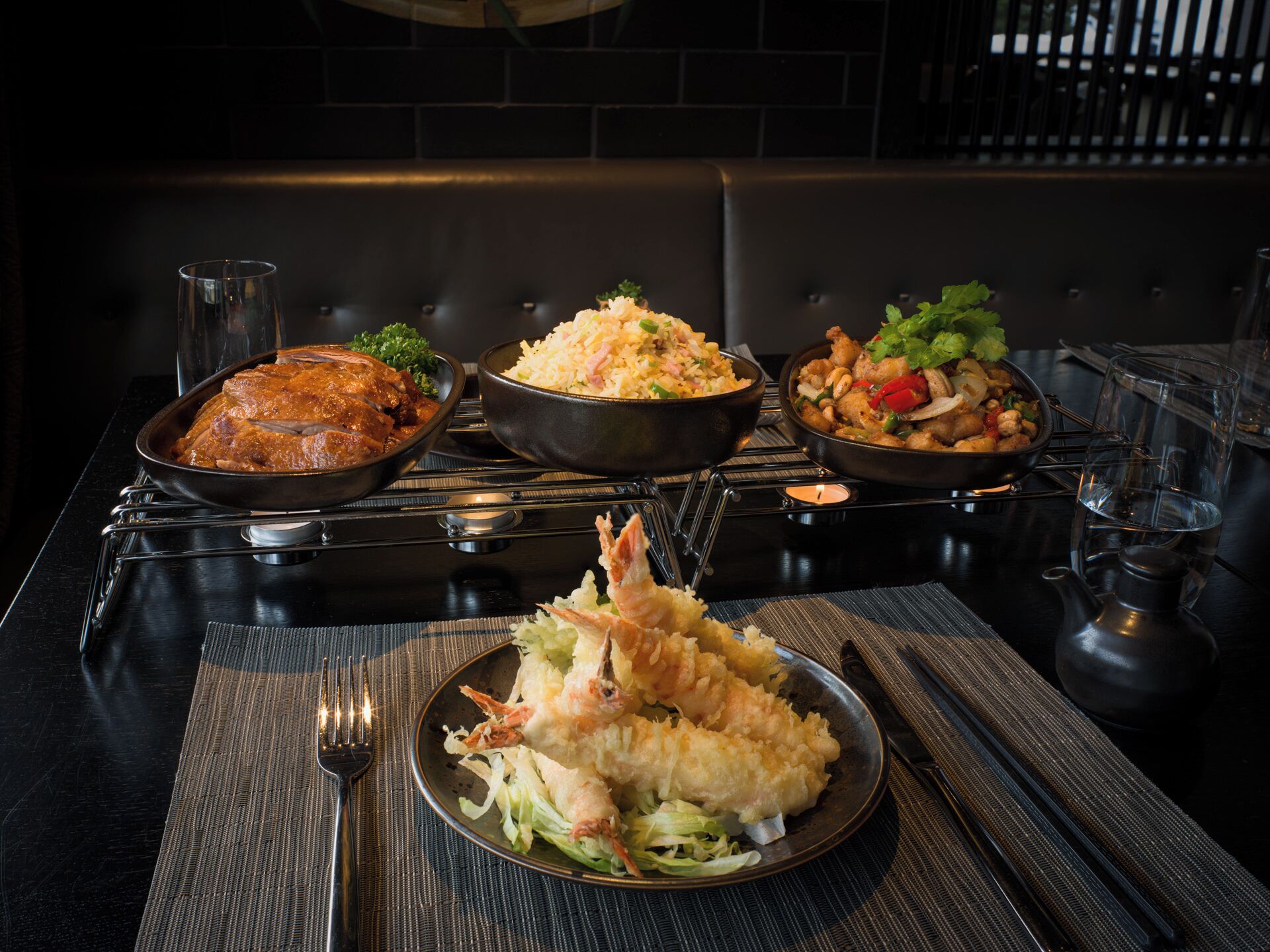 A dining table with three dishes: a bowl of rice, a bowl of curry, and a plate of tempura.