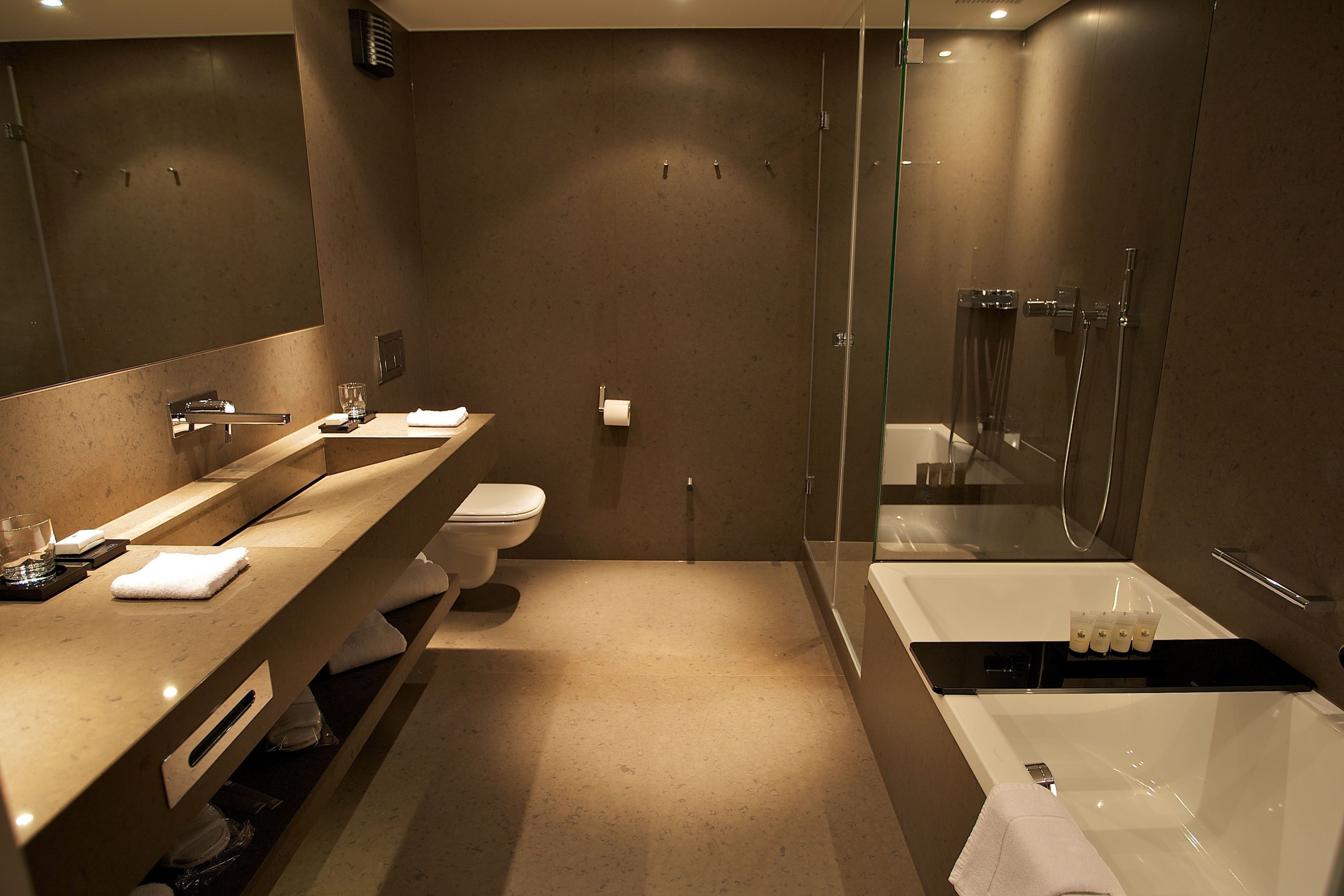 Un baño moderno con un espejo grande, un lavabo, un inodoro y una bañera.