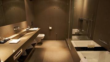 Un baño moderno con un espejo grande, un lavabo, un inodoro y una bañera.