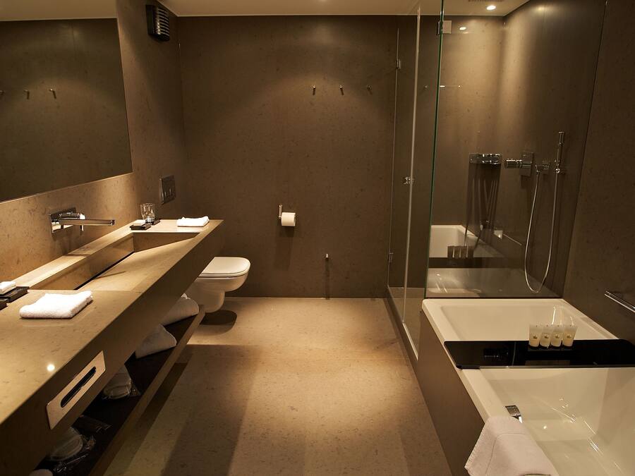 A modern bathroom with a large mirror, a sink, a toilet, and a bathtub.