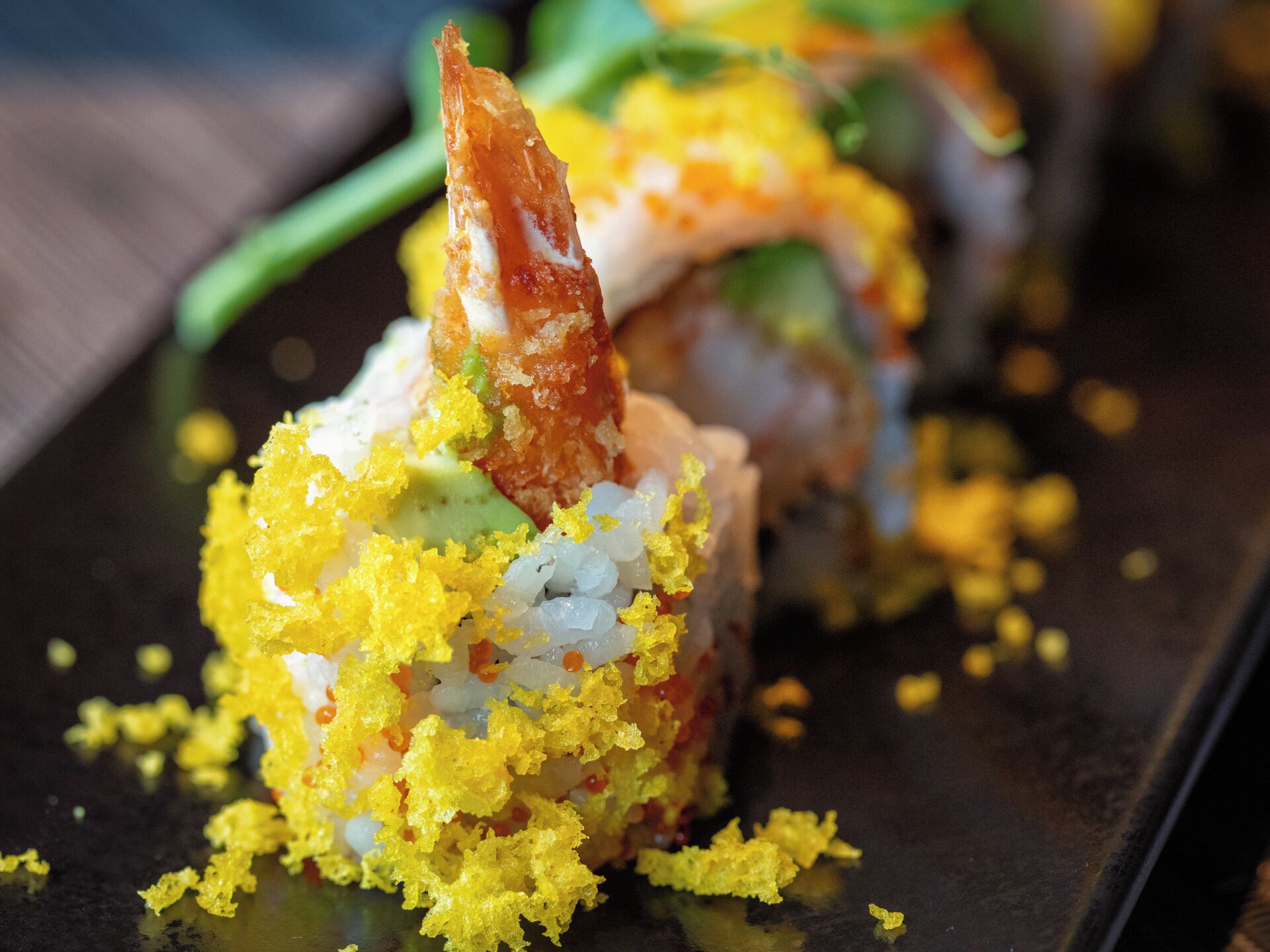 Un plato de sushi con cobertura marrón dorado y guarnición amarilla.