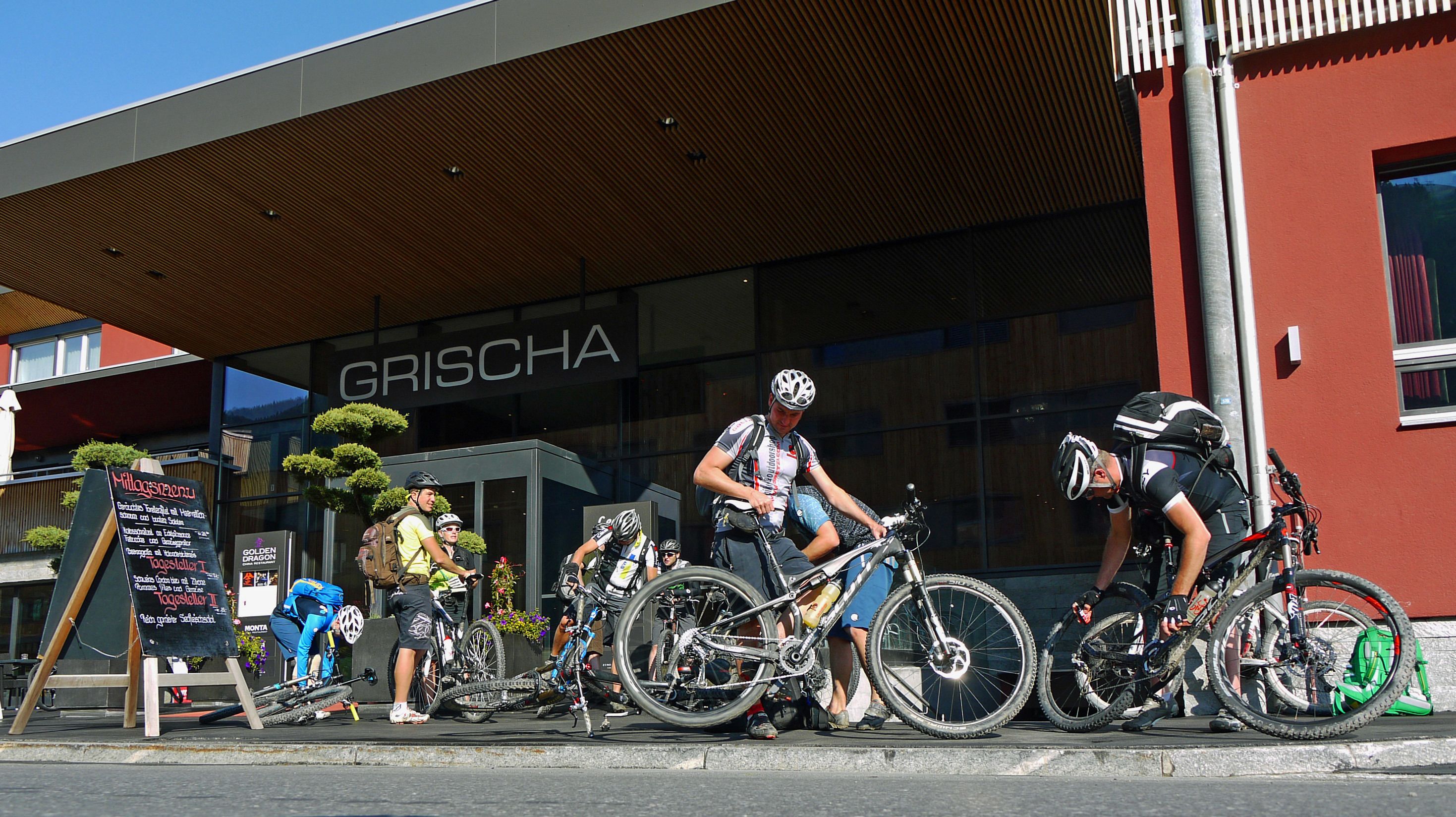 Varias bicicletas estacionadas frente a un edificio con un letrero que dice "GRISCHA".