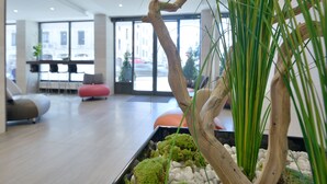 Un intérieur moderne agrémenté d’un jardinier en bois, d’un coin salon et de grandes fenêtres.