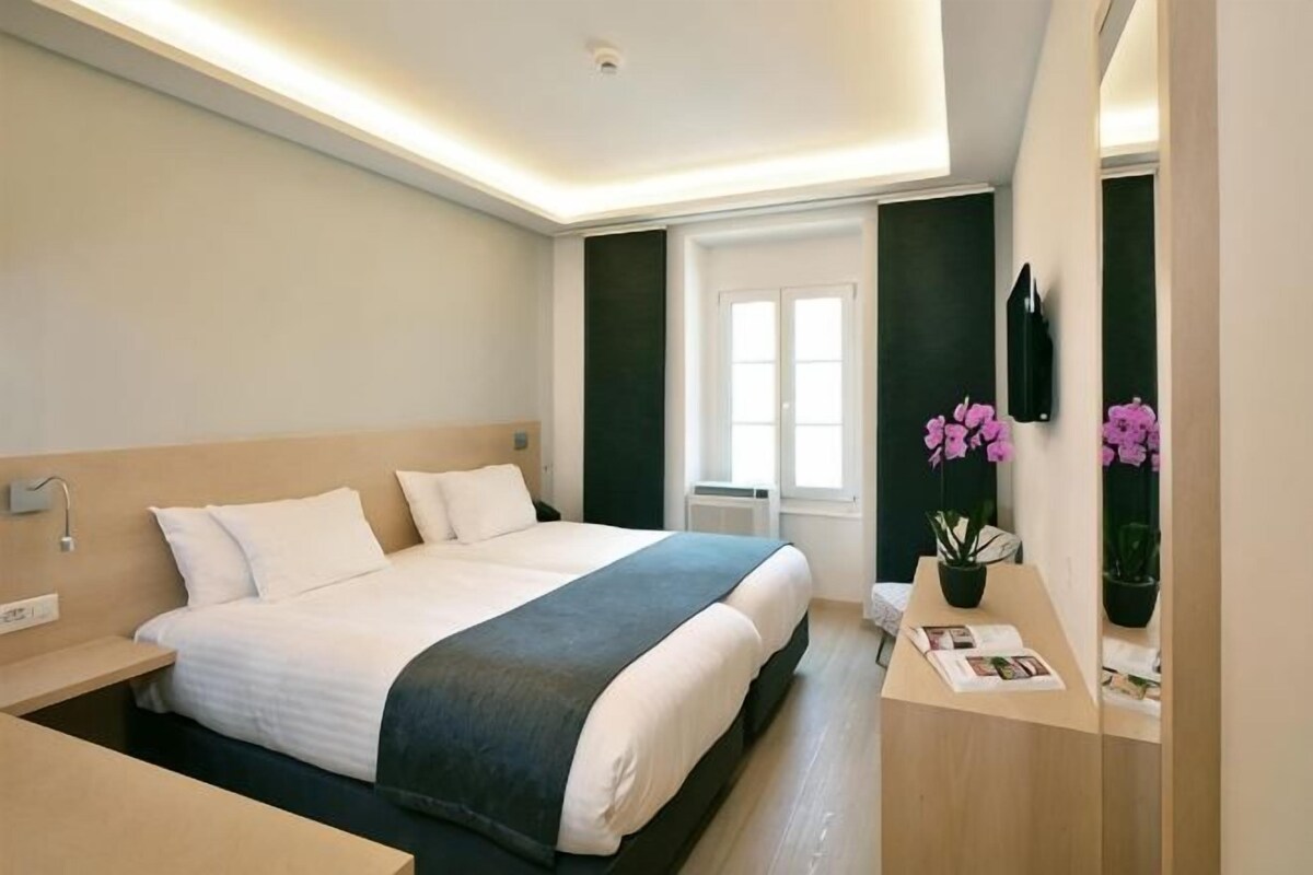 Una habitación de hotel con cama, mesita de noche y espejo.